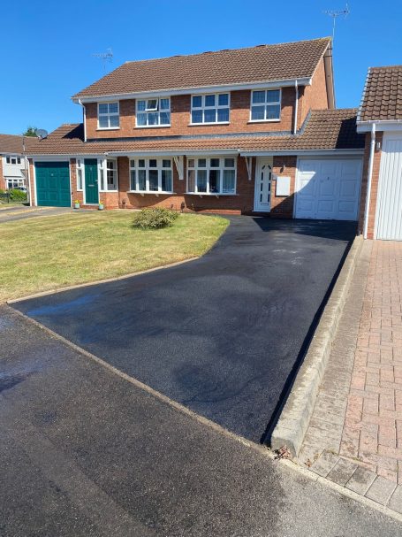 Tarmac Restoration A brick house with a tarmac driveway and well-maintained front garden.